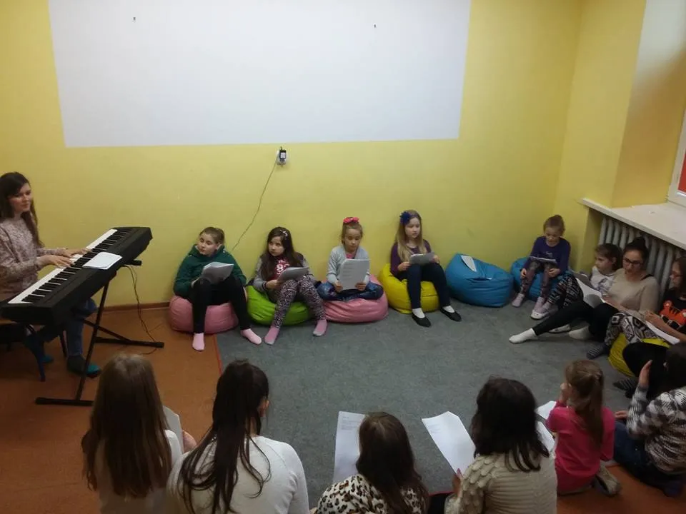 Zdjęcie przedstawia dzieci z placówki w pokoju z żółtymi ścianami podczas przygotowań do koncertu.