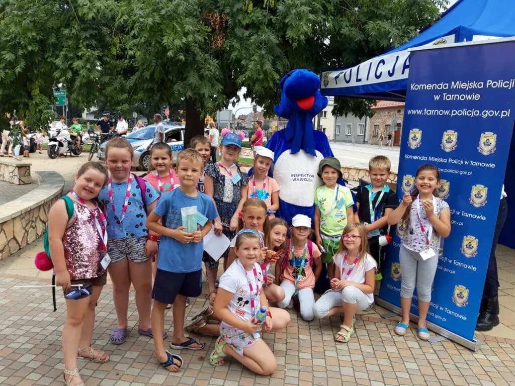 Obraz przedstawia wychowanków podczas święta Policji w Żabnie. Na zdjęciu możemy ujrzeć wychowanków wraz z maskotką tamtego wydarzenia.