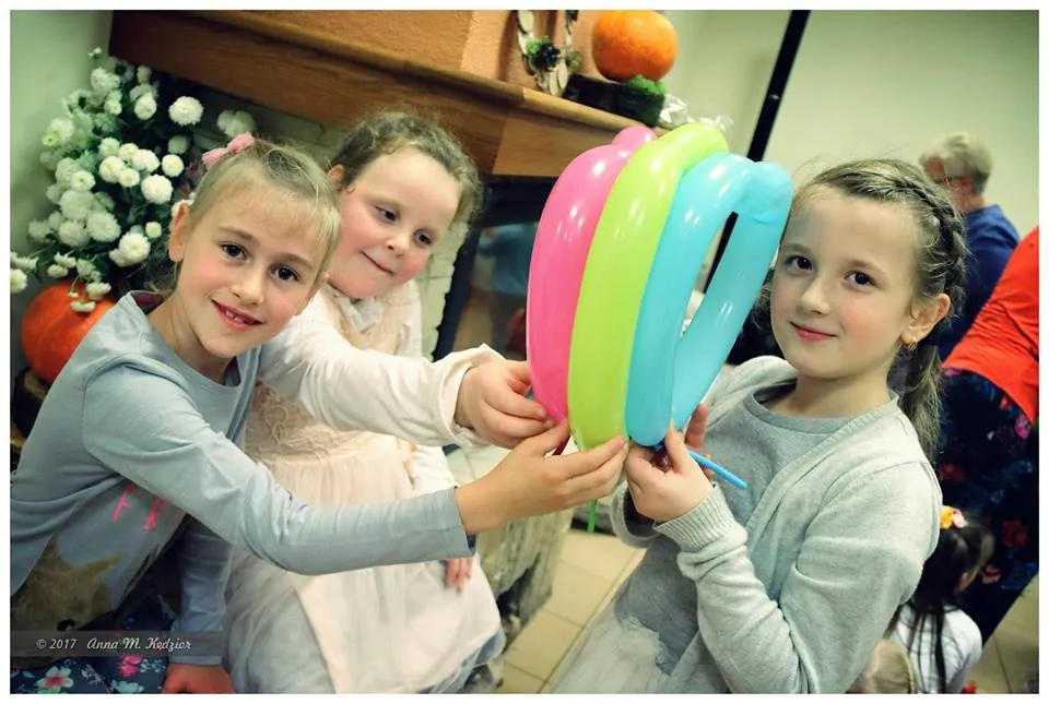 Zdjęcie przedstawia dzieci trzymające przedmioty w kształcie serc w kolorach różowym, żółtym i niebieskim.