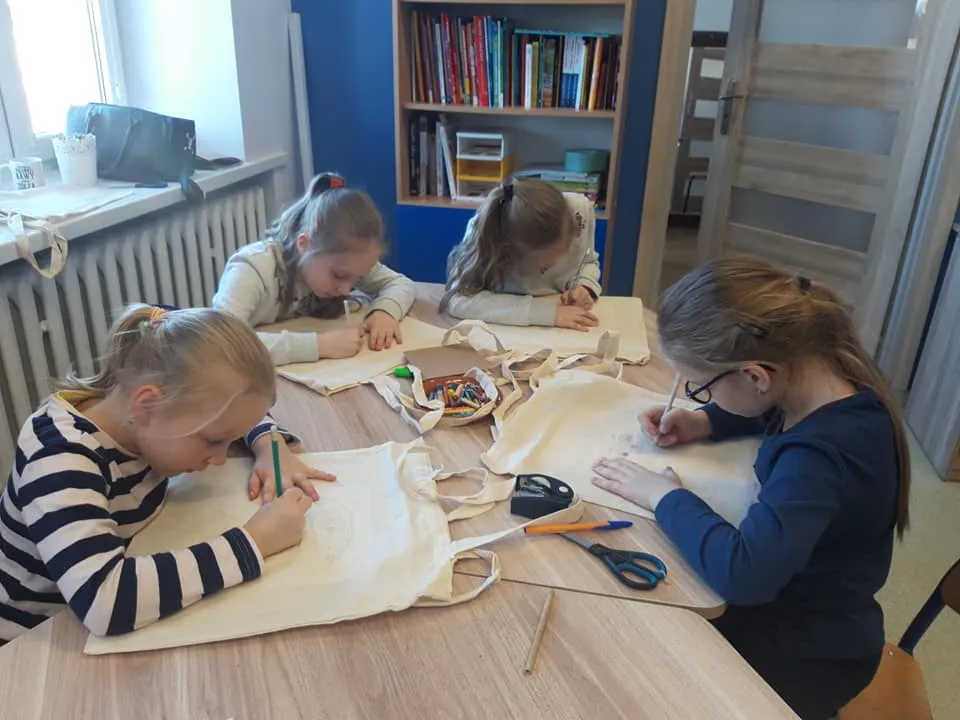 Obraz przedstawia wychowanków SPWD wykonujących personalizowane torby ekologiczne na zakupy.