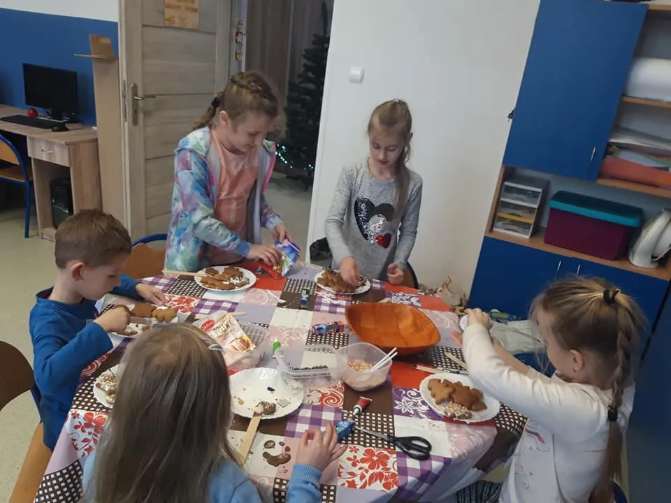 Na zdjęciu widać piątkę dzieci przy stole przygotowujące pierniki.