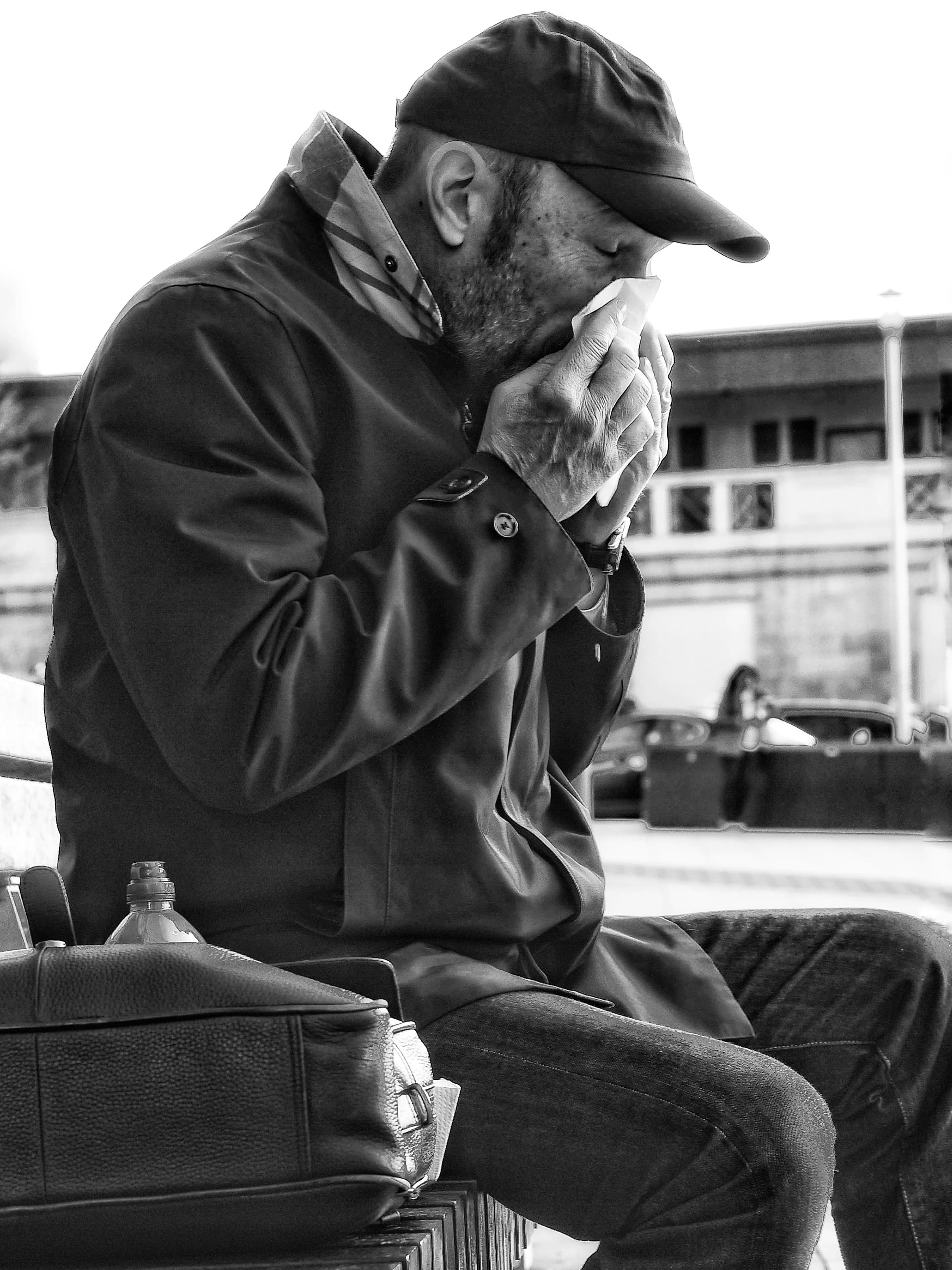 Osoba chora oczyszczająca nos siedząca na zewnątrz